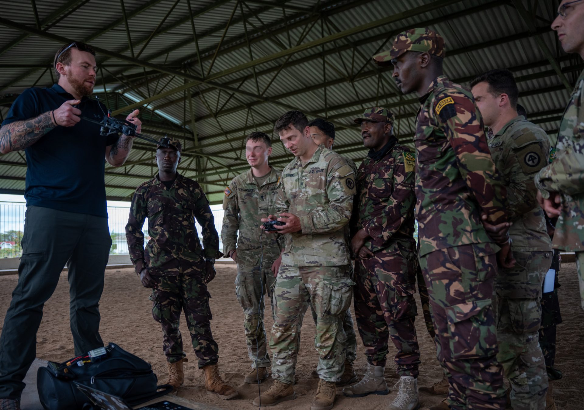 Instructor briefing a group of uniformed service members on FPV drone controls during flight training
